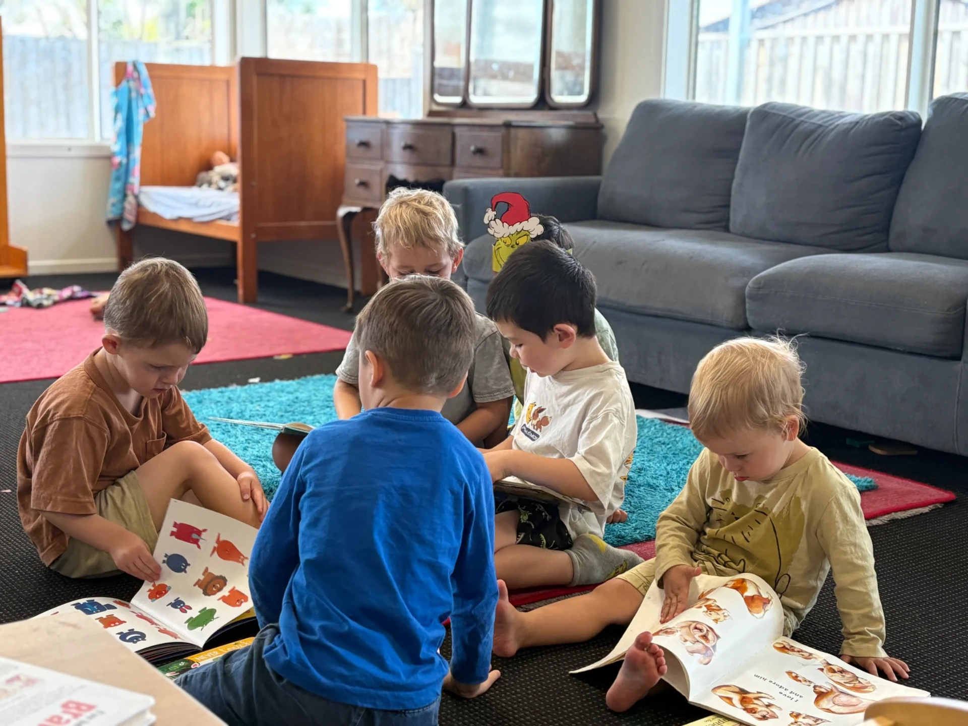 Tamariki sitting together on the rug looking through picture books