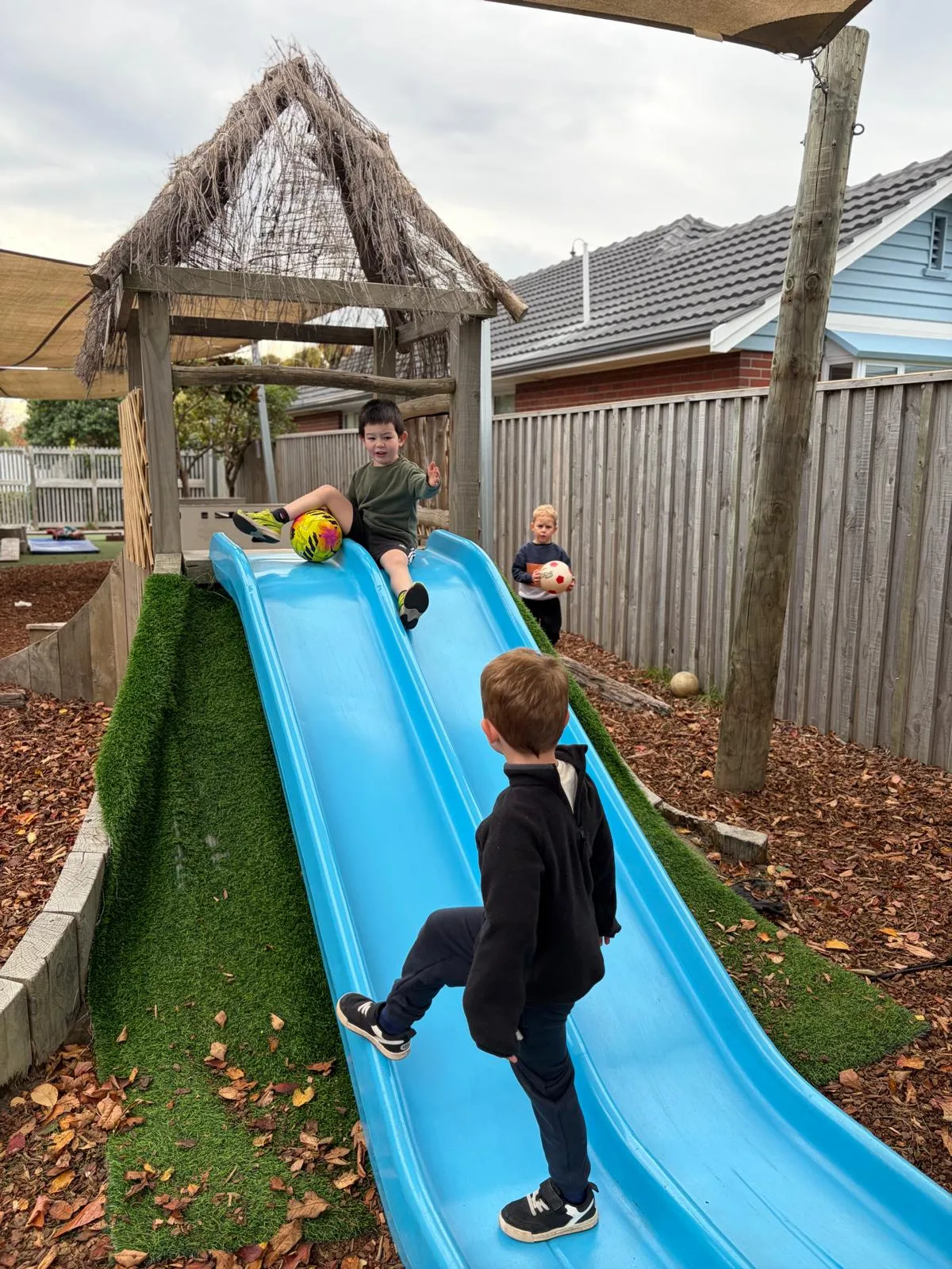 Tamariki taking turns on the blue slide in the Wonderhub playground
